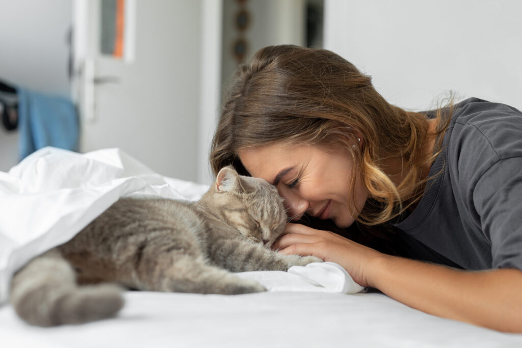 Cat owner putting their head lovingly on the head of their grey cat